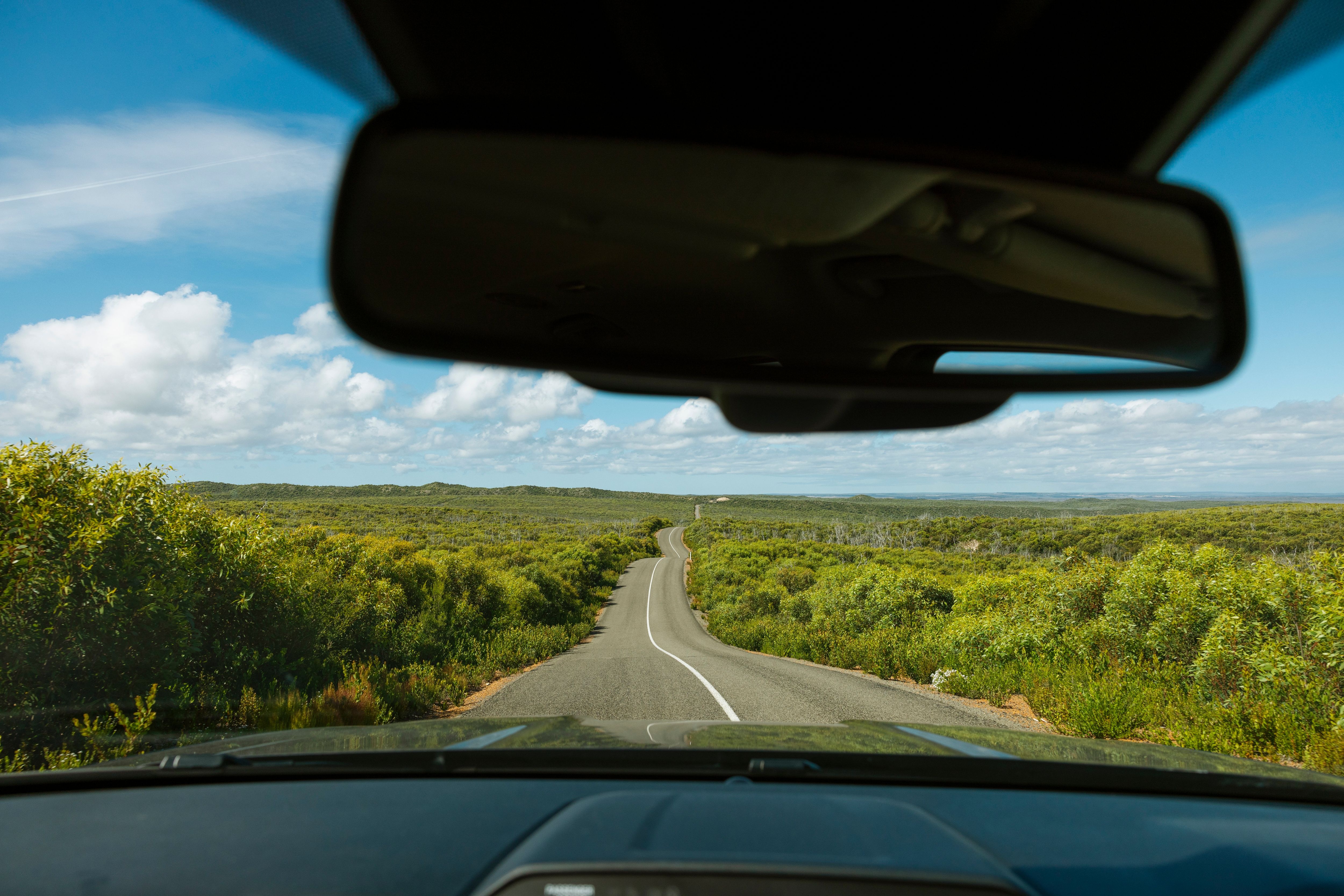 blue water with a car parked on the white sands along the shoreline
