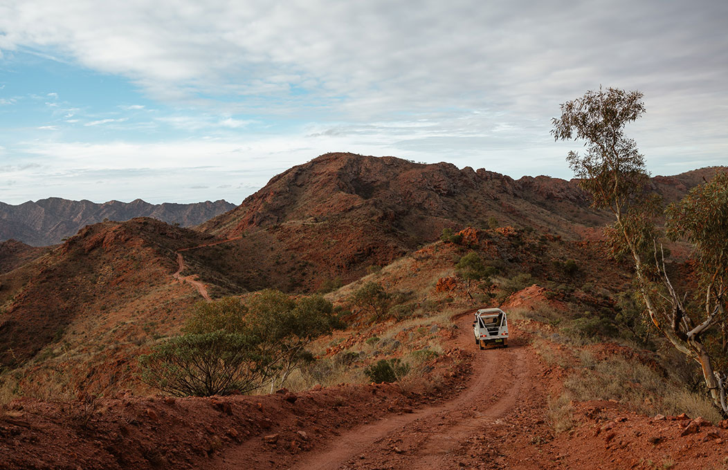 an orange mountain landscape with a 4x4 car driving down a trail