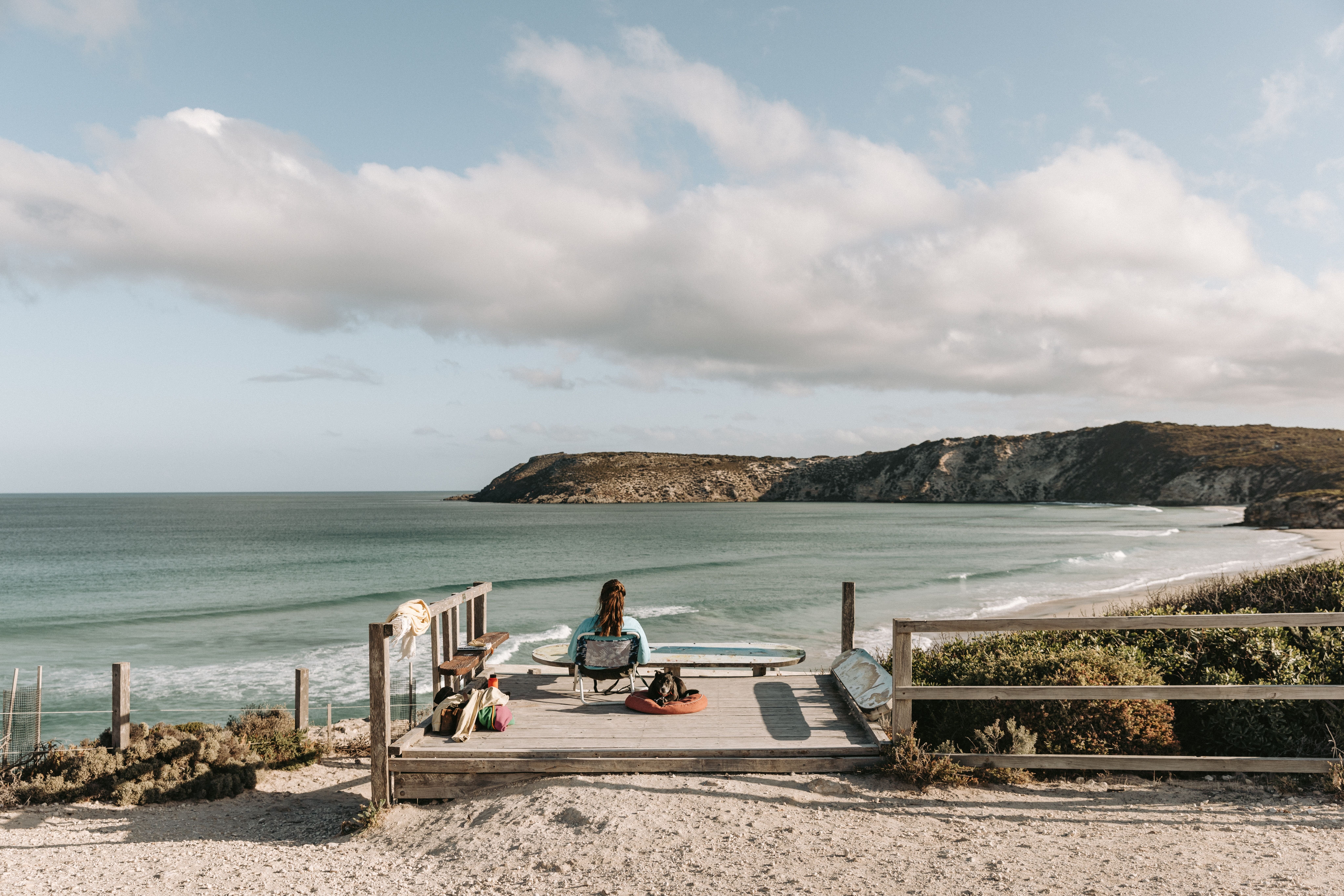 Person relaxing and gazing over the waves and cliffs at Pennington Bay