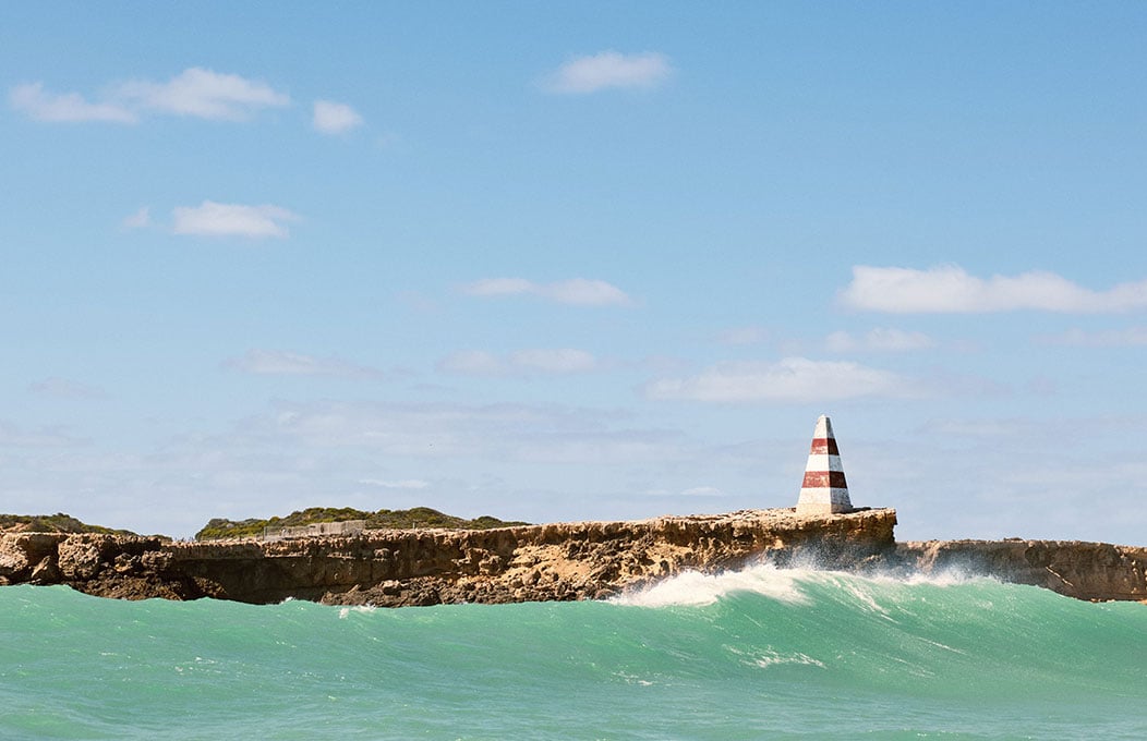 Obelisk on the edge of a cliff beside blue ocean