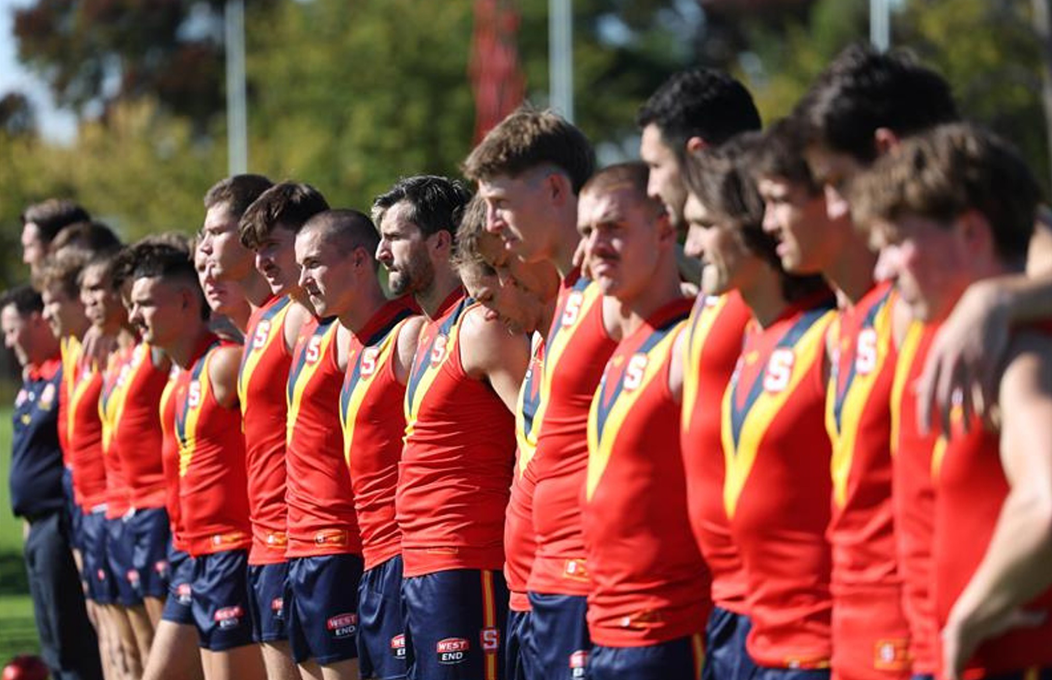 gold coast suns player diving down to grab AFL ball 