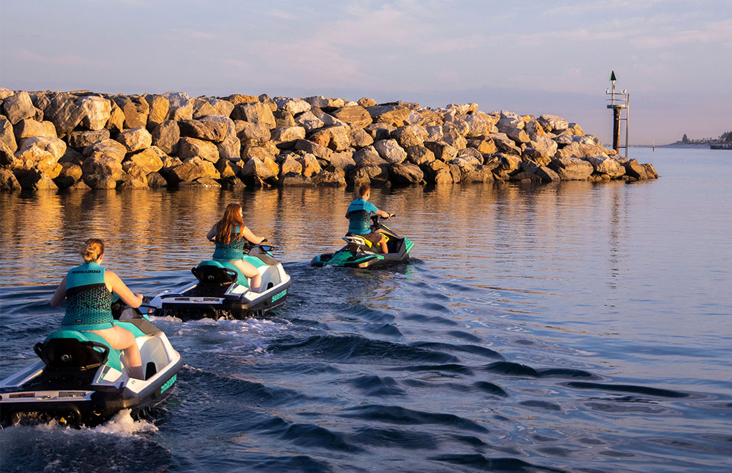 Three people head out on jet skis in West Beach 