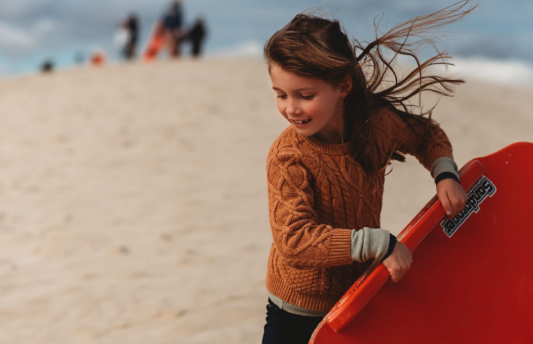 young girl sandboarding at Little Sahara