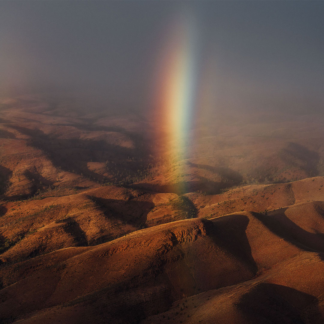 a rainbow beam shining down between the dark ranges