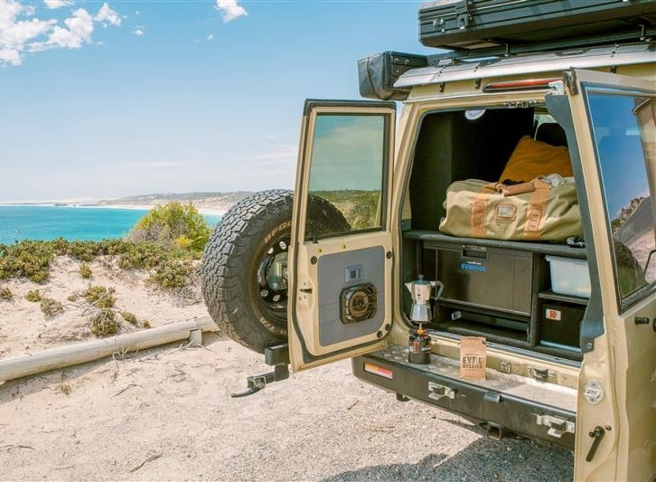 A 4WD with boot doors open stopped in the sand by an Eyre Peninsula beach