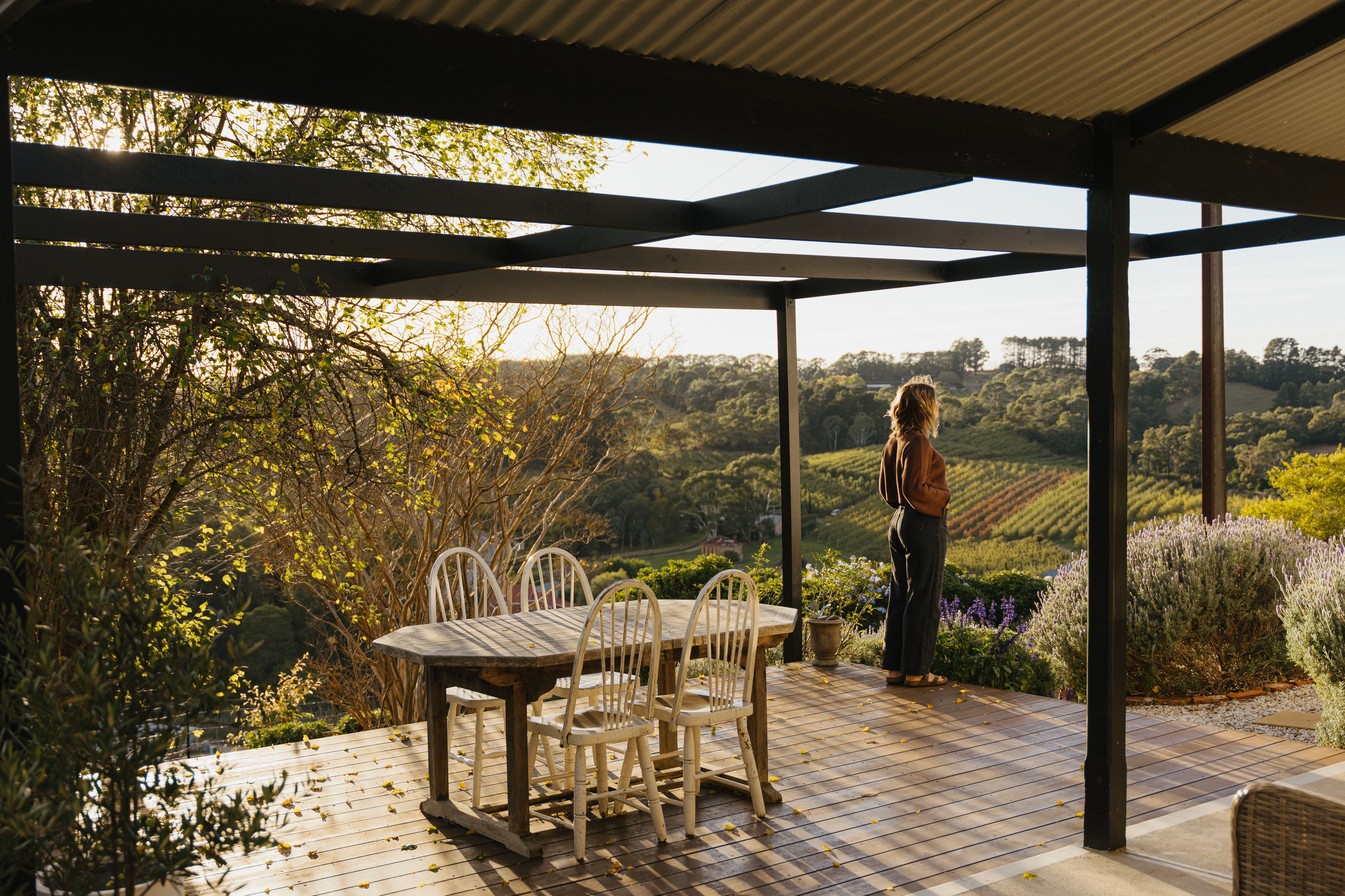 Person standing on a deck looking over rolling hills