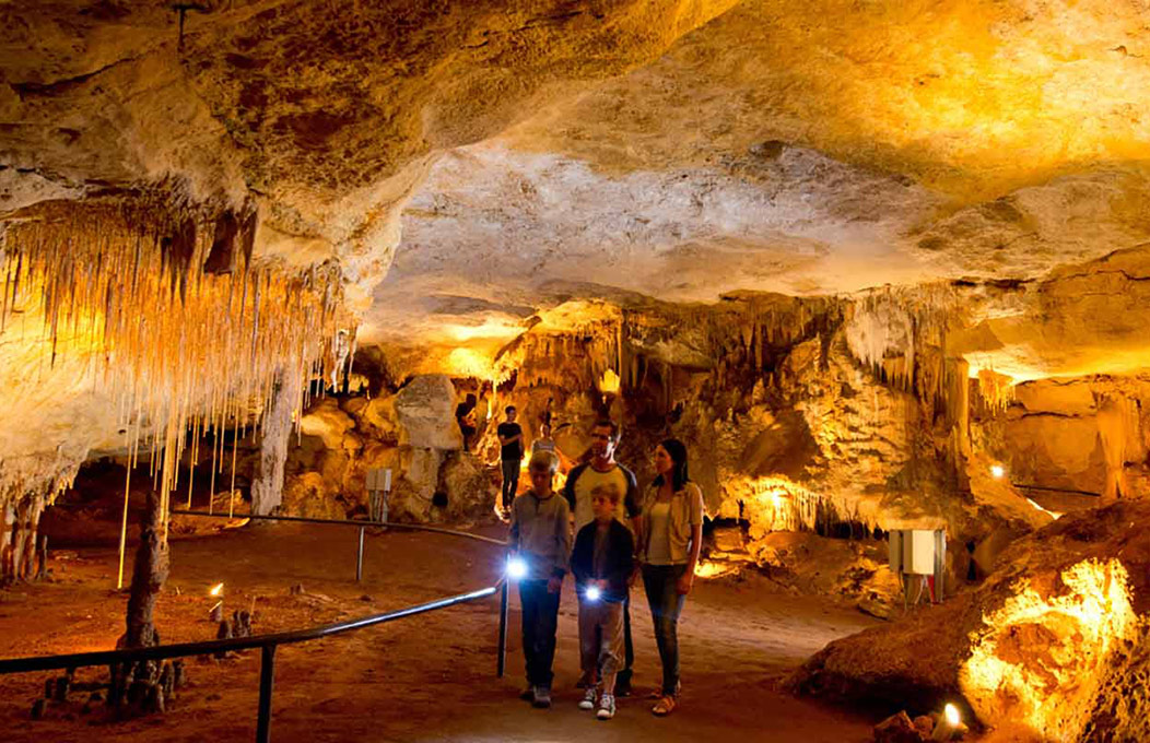 Brightly lit cave system with people exploring inside